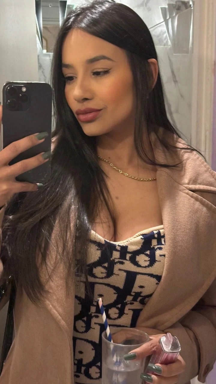 Alline takes a picture in the mirror, she looks happy and smiles softly