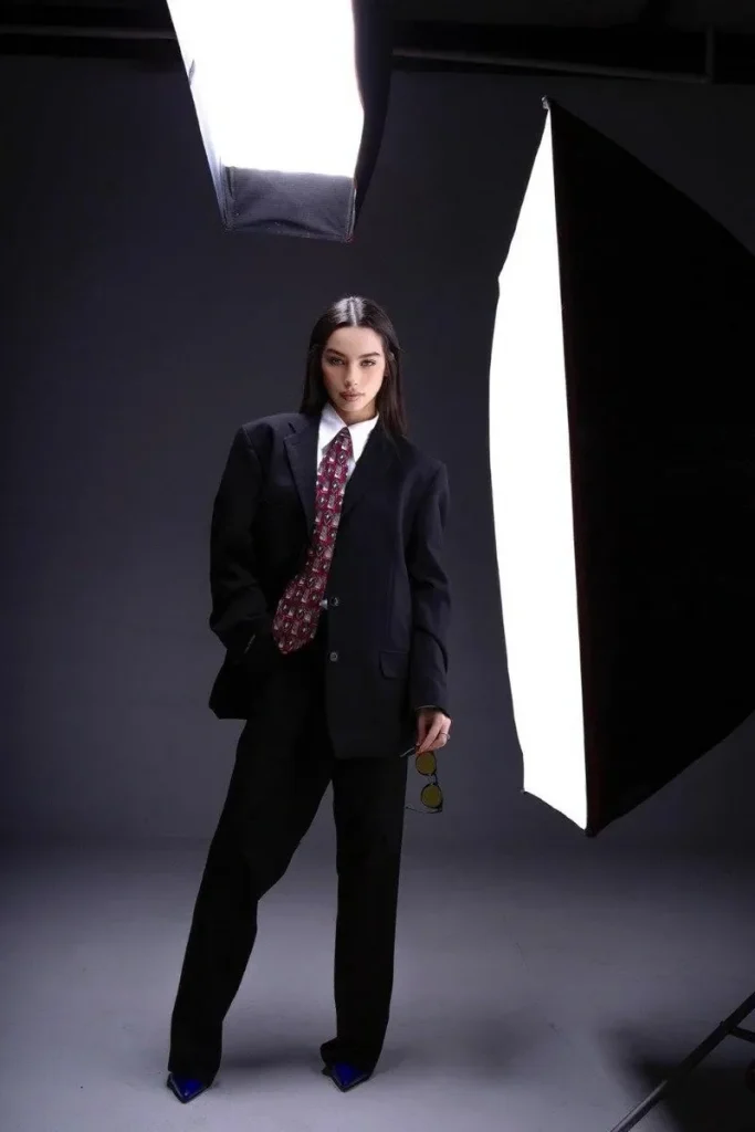 Anis is brightly made up and dressed in a costume, she's at a photo shoot